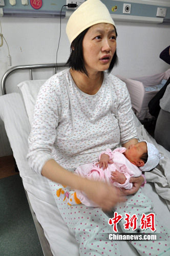 邓美华抱着刚出生的女儿说，妈妈要用肾救你亲哥哥。 刘柱 摄