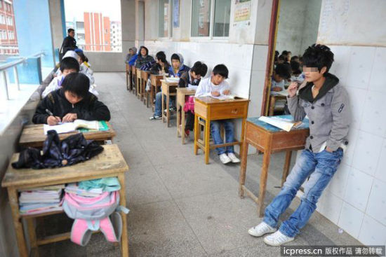 楼道两边坐满考试的学生，画面前的这名学生连凳子都没有。图片来源：东方IC