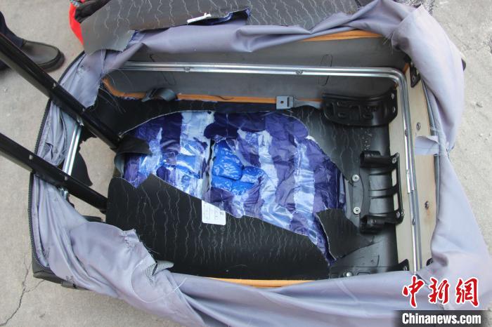 图为民警从乘客携带的行李箱夹层中查获冰毒。　韦立鹏 摄
