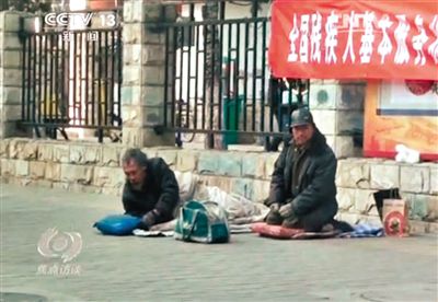 工人体育场北路，两位乞讨者路边乞讨，并轮流扮成“病人”（躺地者）。央视截图